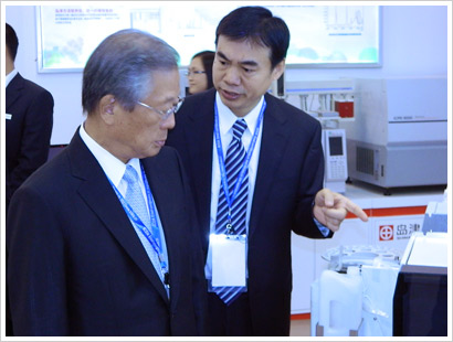 岛津曹磊先生向服部会长（左一）介绍岛津分析装置